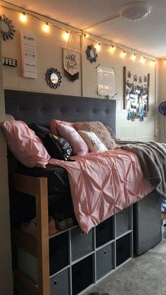 a bed with pink sheets and pillows on top of it next to a book shelf