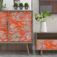 an orange and blue floral dresser next to a brick wall with potted plants on it