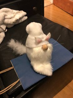 a stuffed animal with a white hat and scarf on it's head sitting on a blue piece of paper