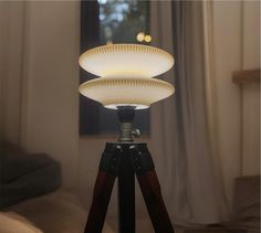 a tripod light sitting on top of a wooden table next to a bed in a room