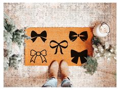 a person standing in front of a door mat with bows on it