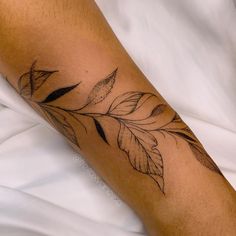 a close up of a person's leg with a tattoo on the arm and leaves