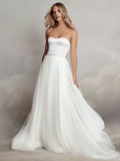 a woman in a white wedding dress posing for the camera with her hands on her hips