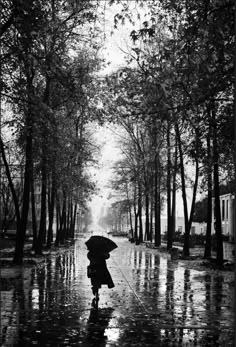 a woman walking down a rain soaked street holding an umbrella