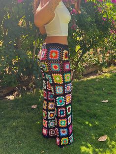 a woman standing in the grass with her hand on her face and wearing a white crop top