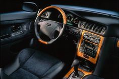 the interior of a car with black leather and wood trims, including steering wheel