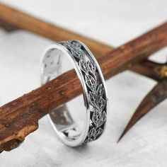 a silver ring sitting on top of a piece of wood next to a wooden stick