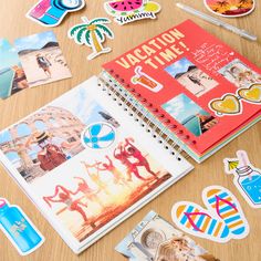 various stickers and magnets on a table with an open notebook in the middle