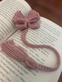 an open book with a pink crochet bow on it and a tassel