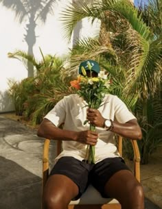 a man sitting in a chair holding flowers