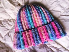 a knitted hat laying on top of a bed