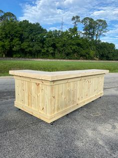 a large wooden box sitting in the middle of a parking lot next to some trees