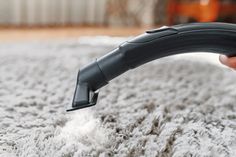 a person is vacuuming the carpet with a hand held vacuum cleaner on top of it