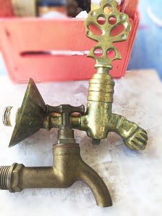 an old brass faucet is sitting on the floor next to a red box