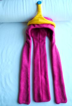 a pink towel with a yellow hanger on it sitting on top of a bed