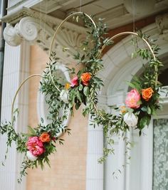 two hoop hanging from the ceiling with flowers and greenery on it's sides