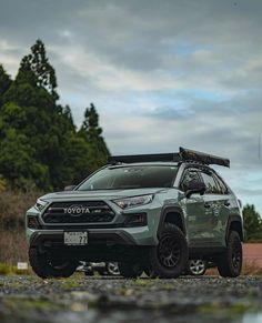 a grey toyota rav parked on the side of a road with trees in the background