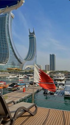 a boat dock with several boats docked in the water and buildings in the background on a sunny day