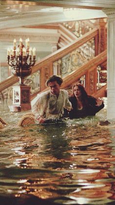 a man and woman are standing in the water at the bottom of an escalator