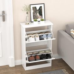 a living room with a couch and a white shoe rack on the floor next to a gray sofa