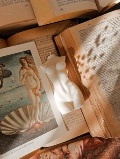 an open book sitting on top of a wooden table next to other books and papers