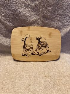 a wooden plaque with two gnomes on it