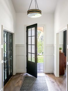 an entryway with a black door and light fixture hanging from it's ceiling