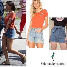 a woman in shorts and an orange shirt is walking down the street with her legs crossed