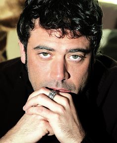 a close up of a person with a ring on his finger and wearing a black shirt