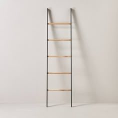 a ladder leaning against a white wall with no one on the floor in front of it