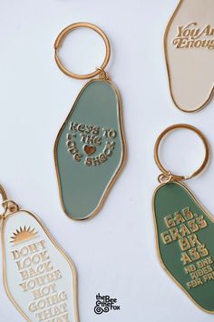 three key chains with different designs on them, one is gold and the other is green