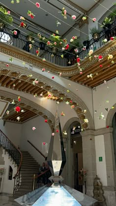 an indoor area with many flowers hanging from the ceiling and stairs leading up to it