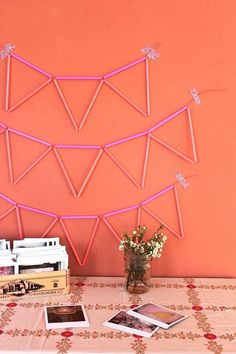 a table topped with pink string art next to a vase filled with flowers and pictures