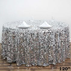 a table covered in silver sequins with two plates on it and one empty plate