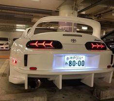 the back end of a white car in a parking garage