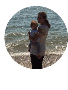 a woman holding a baby on the beach