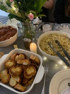 the table is set with many dishes of food and utensils, including pasta