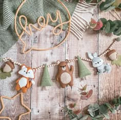 several wooden animals hanging on a string with leaves and foliage in the background, along with an ornament that says love