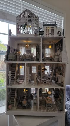 a doll house with lots of windows and furniture in the middle of it's room