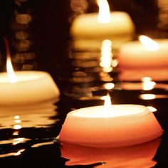 several lit candles floating on top of water