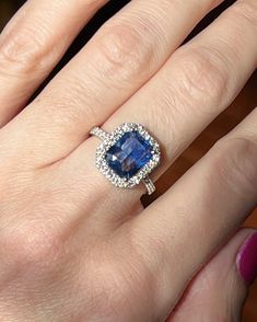 a woman's hand with a ring on it and a blue stone in the middle