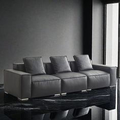 a couch sitting on top of a black marble floor next to a large glass window