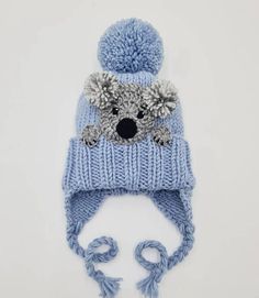 Knit pom pom hat with earflaps, strings and a crochet Koala applique sewn onto. Cute winter outfit for kids, teens and women as well:) Choose your size and color using drop down menu. Available sizes: Toddler 1-3yr 18-20(46-50cm) Child 3-10yr 19-21(49-52cm) Teens/Adult Small 20.5-22(52-55cm) Adult Whimsical Hand Knitted Beanie Bonnet, Whimsical Hand-knitted Beanie Bonnet, Cute Hand Knitted Winter Bonnet, Whimsical Hand-knitted Cap Hat, Whimsical Hand Knitted Cap, Playful Warm Bonnet Cap, Playful Knitted Bonnet, One Size, Playful Knitted Hats For Cold Weather, Cute Knitted Beanie Bonnet