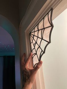 a person holding up a stained glass window with a spider web design on it's side