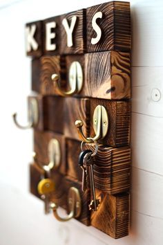 a key holder made out of wooden blocks with keys hanging on the hooks and letters