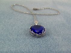 "This faceted dark blue sapphire is set in a round floral designed bezel frame. A fan shaped bail holds this deep blue gem on an oxidized silver cable link chain, closed with a lobster claw clasp. The 18mm (3/4\") Czech glass gem is dark blue and has many facets that reflect the light. The chain in 20\" in length. Chain length can be ordered from 16\" up to a 24\" with no additional cost. Just message me with your request at time of purchase. This lovely sparkling cobalt blue necklace would enha Royal Blue Jewelry For Gifts, Royal Blue Jewelry For Gift, Royal Blue Jewelry Gift, Royal Blue Jewelry For Formal Occasions, Formal Royal Blue Round Jewelry, Victorian Style Blue Round Pendant Jewelry, Victorian Sapphire Round Jewelry, Nickel-free Round Sapphire Necklace, Czech Glass Necklace