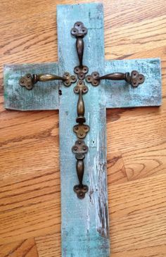 an old wooden cross with metal handles on a wood floor in front of a wall