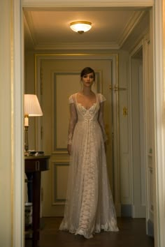 a woman in a white dress is standing in the hallway with her hands on her hips