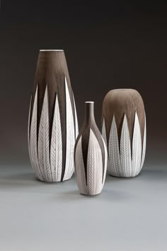 three vases with different designs on them sitting next to each other in front of a gray background