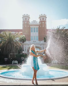 a woman standing in front of a fountain with water spewing out of it